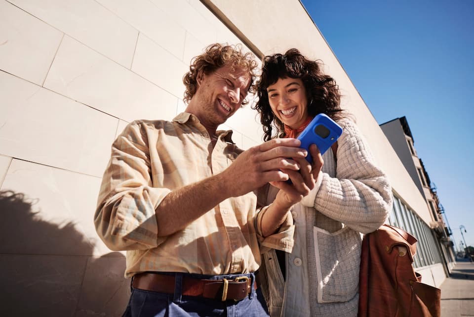 Duas pessoas sorrindo enquanto conferem algo no celular